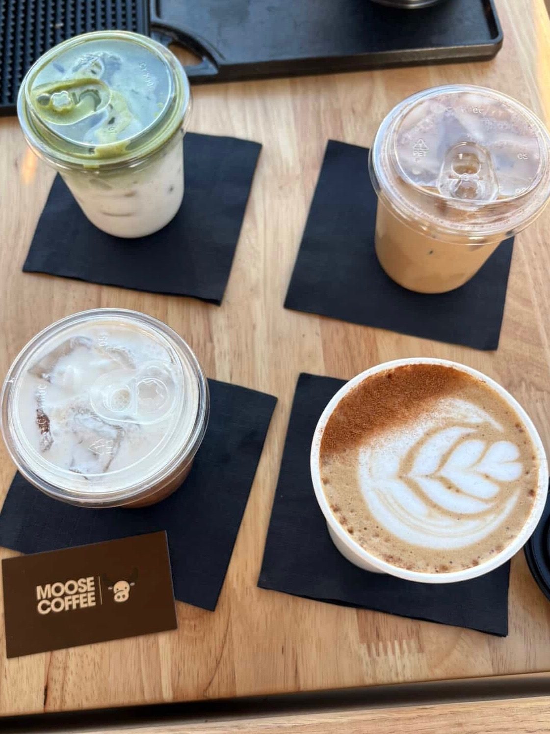 Four Moose Coffee drinks laid out with branded cards
