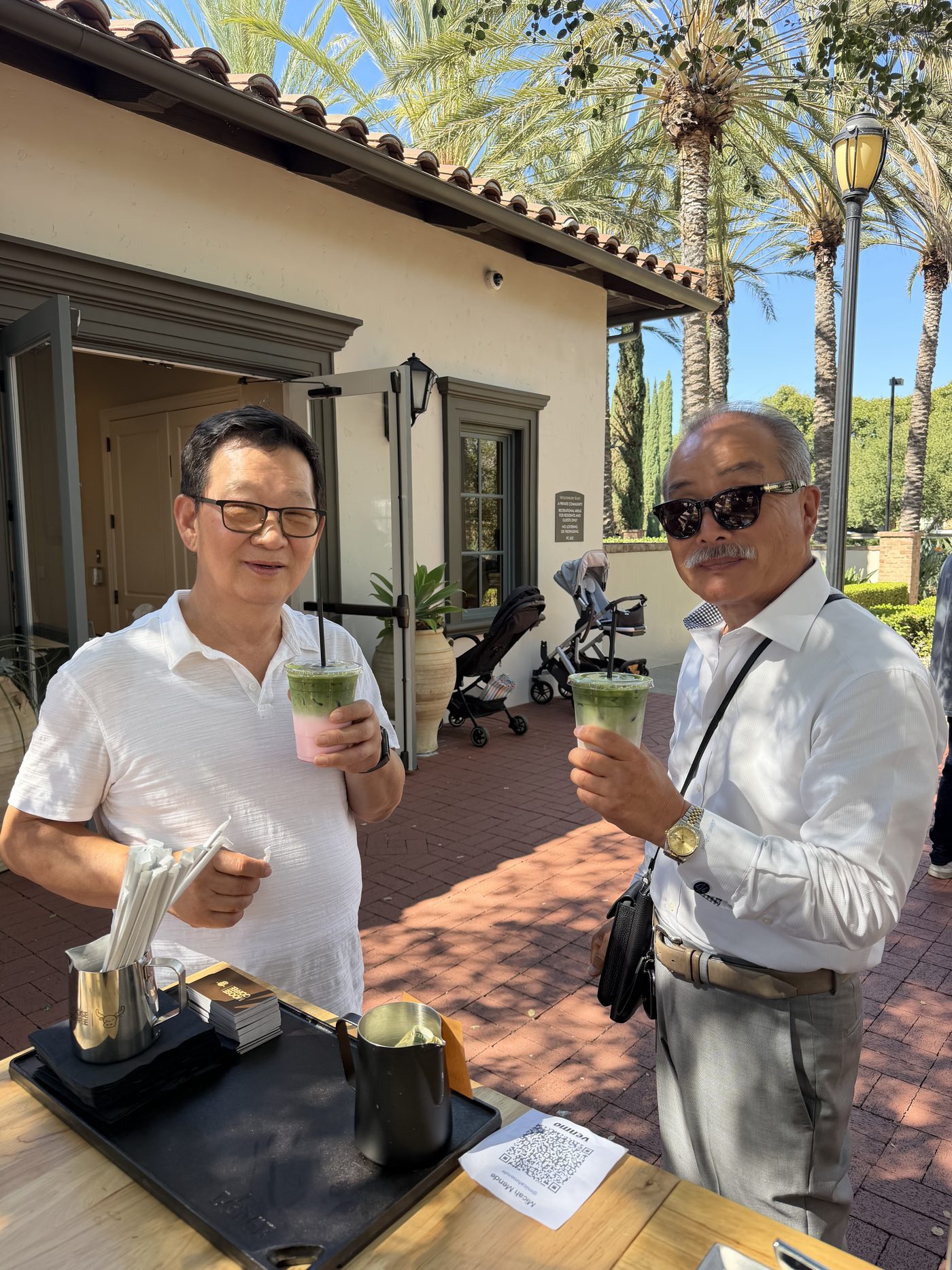 Two guests holding iced matcha drinks beside the Moose Coffee cart