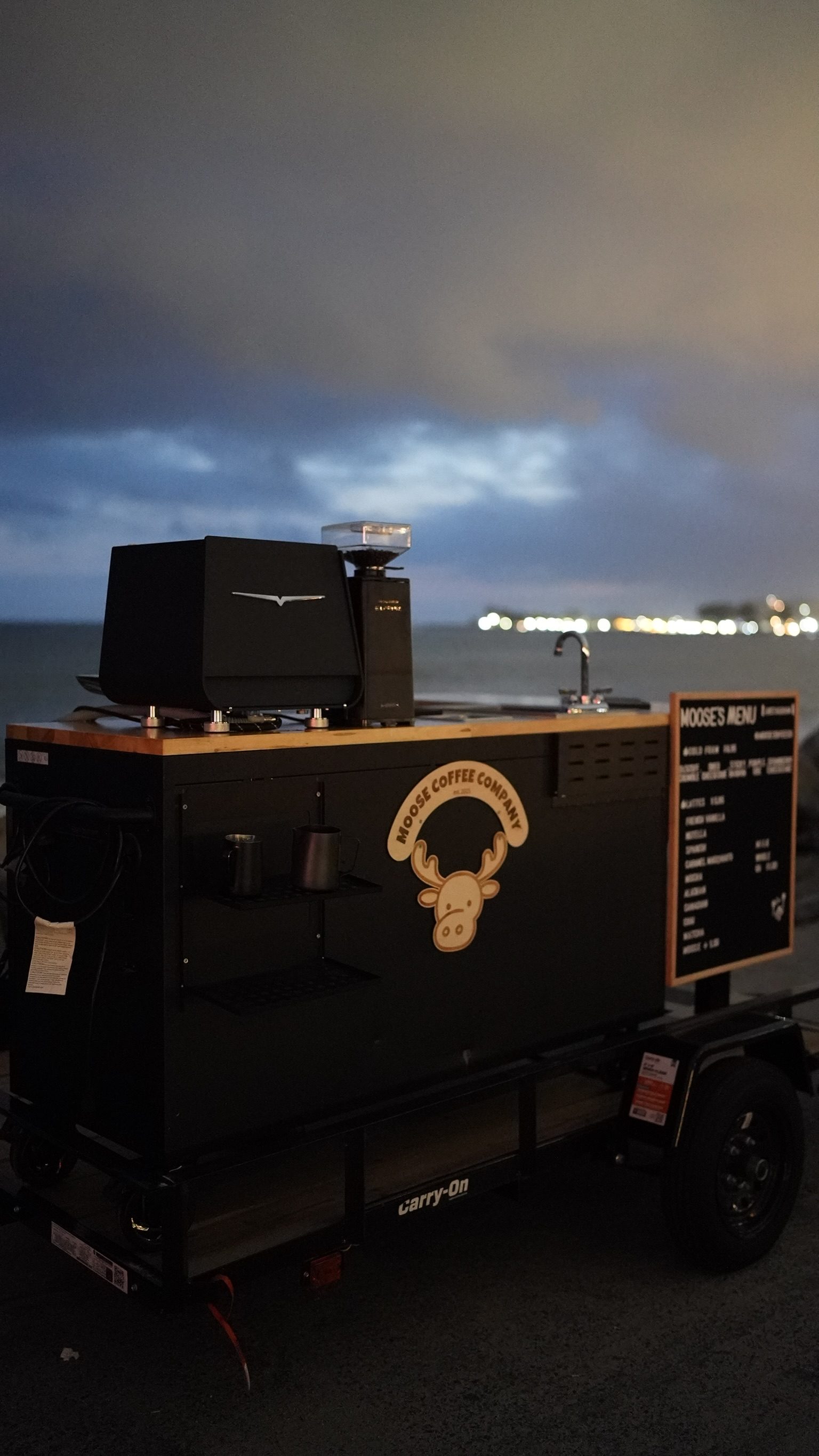 The Moose Coffee cart set up by the water at dusk